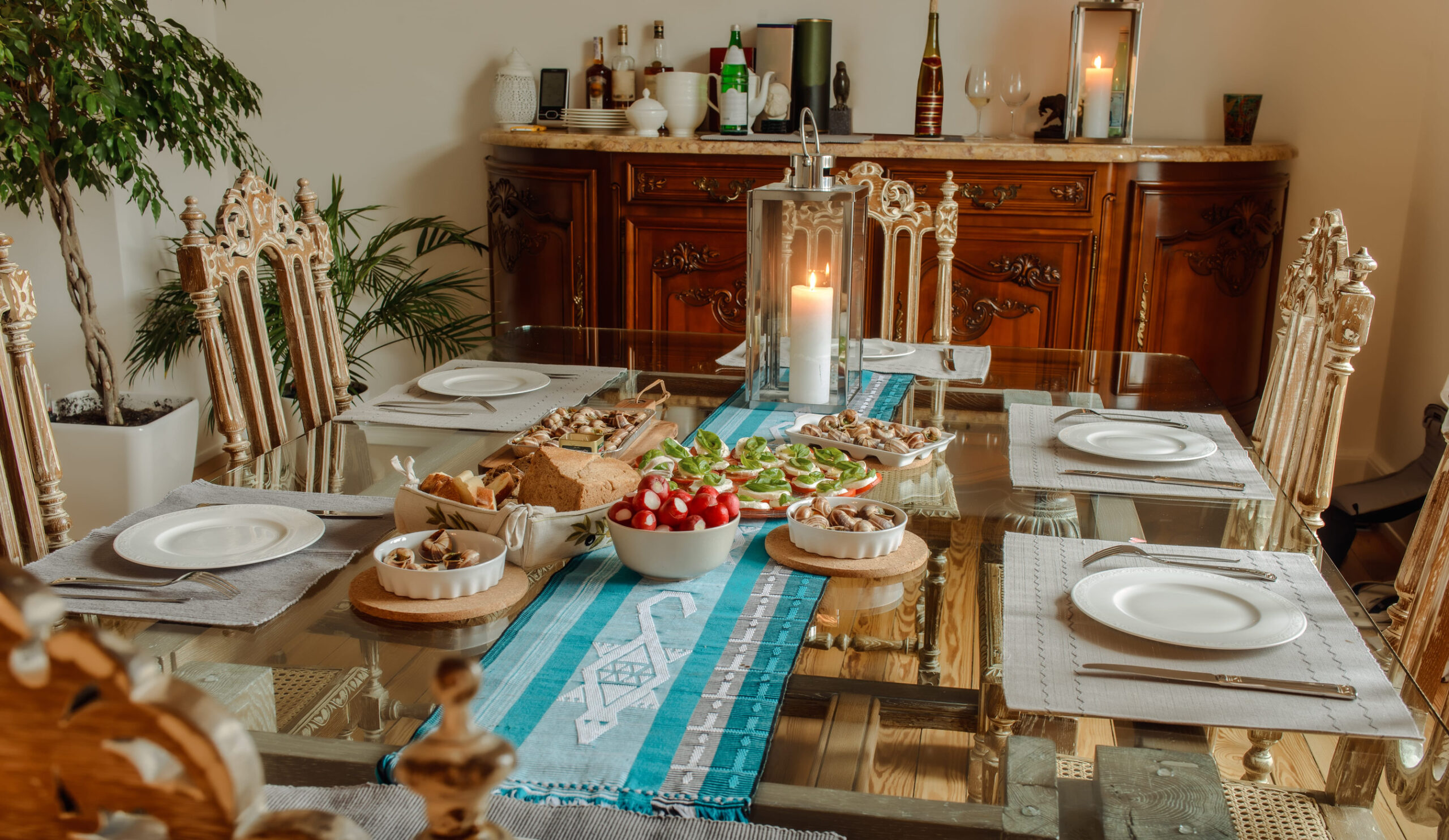 Ready to eat tomatoes with cheese , snails and bread on a table in a beautiful home interior on background Vintage chest