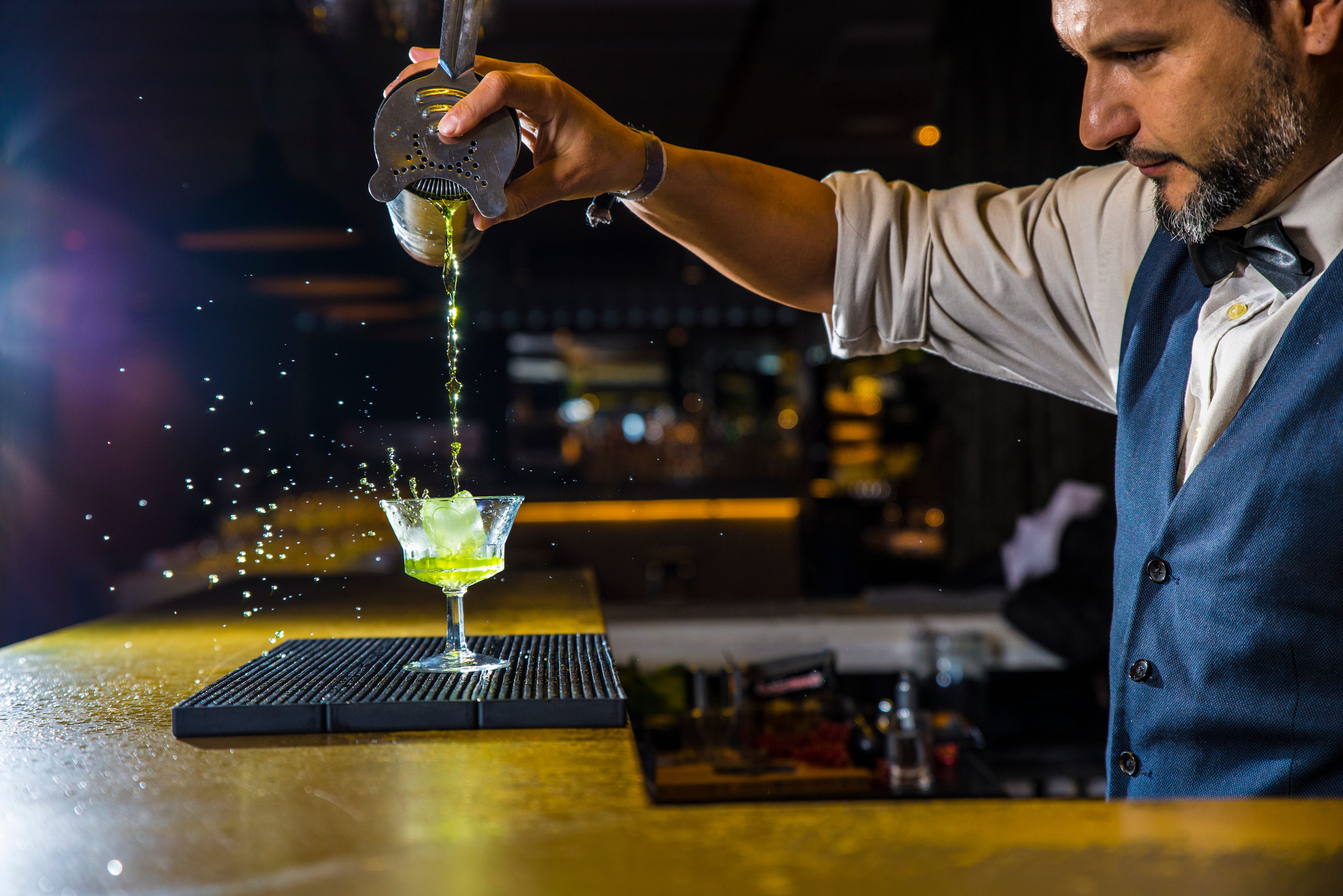 Expert barman is making cocktail at night club
