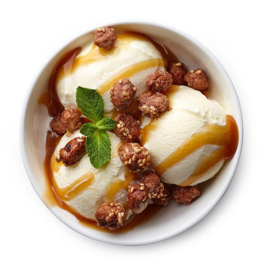 Indulge in a delightful bowl of creamy vanilla ice cream topped with crunchy caramelized nuts and a drizzle of rich caramel sauce, garnished with a fresh mint leaf for that perfect touch of freshness. Image Credit: baibaz/ 123RF