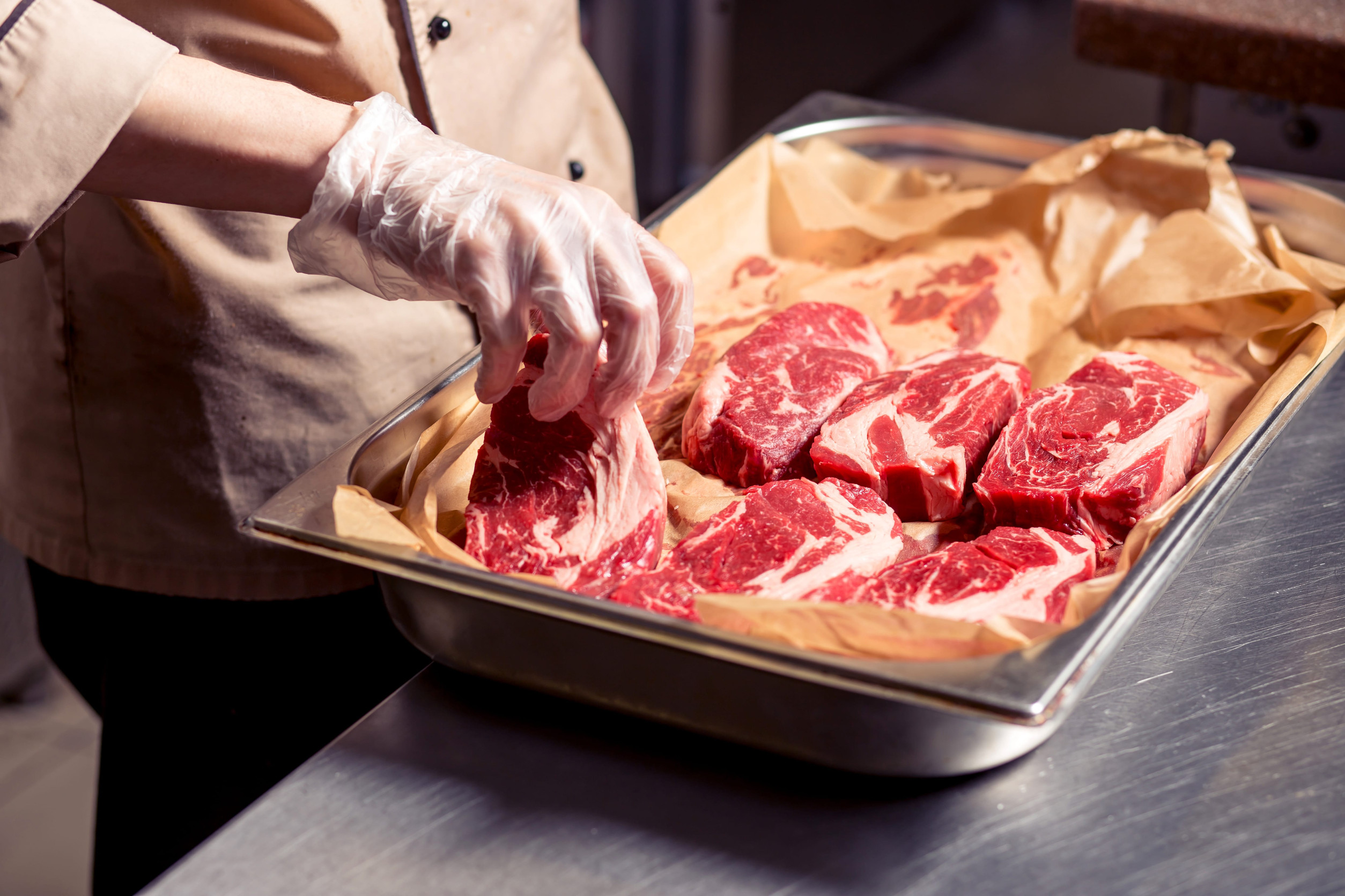Male chef cooking lamb ribs. Cook preparing delicious meat at restaurant