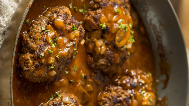 Savor the rich flavors of homemade Salisbury steak, perfectly seared and smothered in a savory mushroom gravy, served in a rustic skillet that brings comfort to the dining table. Image Credit: bhofack2/ 123RF