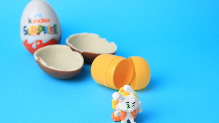 Discover the whimsical world of Kinder Surprise, where yummy chocolate meets delightful surprises! A curious character peeks out from a golden capsule, inviting adventure with each layer peeled away. Image Credit: liudmilachernetska/ 123RF