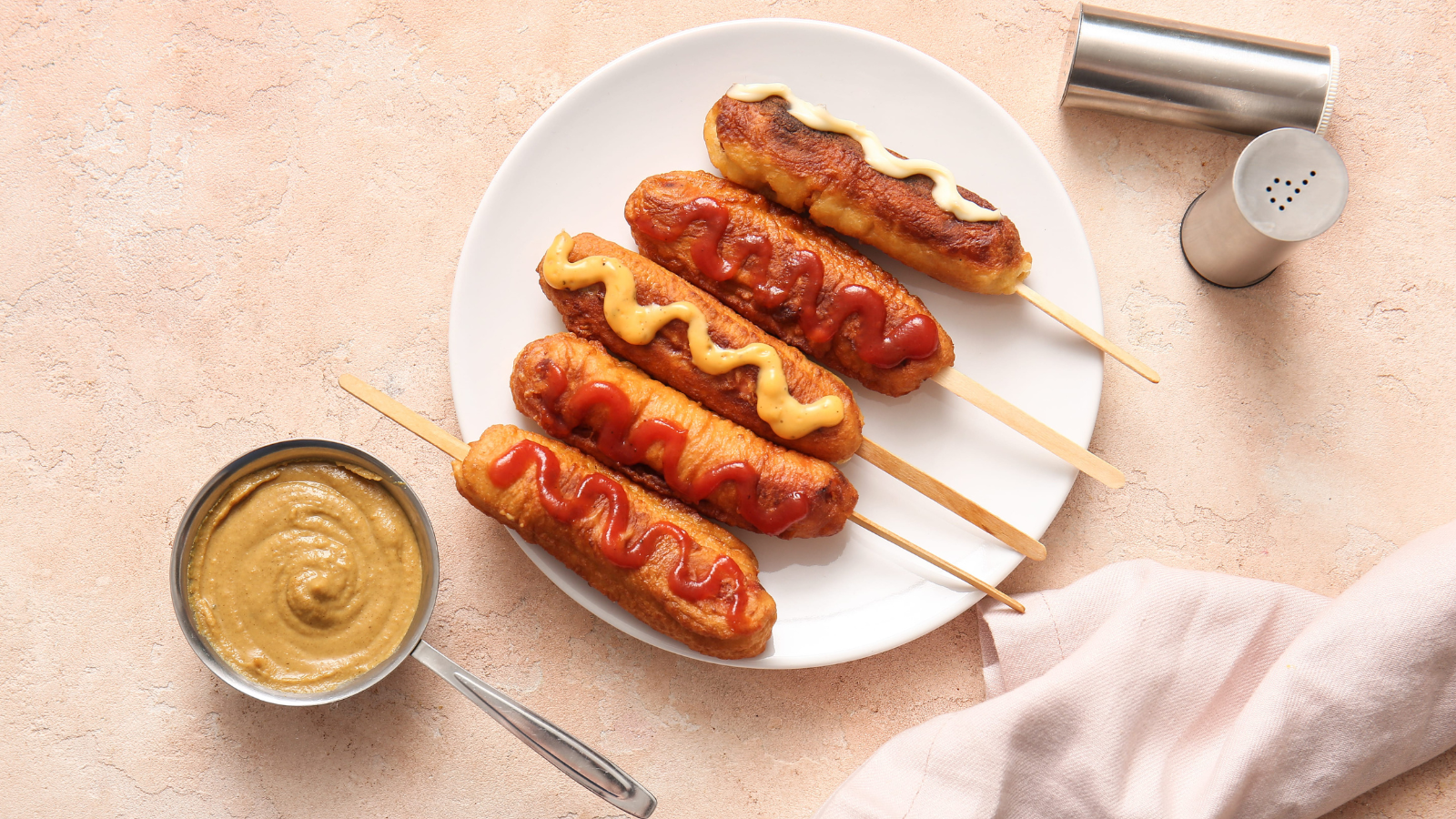 Savor the summer with a delightful platter of crispy corn dogs, each drizzled with creamy mustard and tangy ketchup, perfect for gatherings or a cozy solo snack. Image Credit: serezniy/ 123RF
