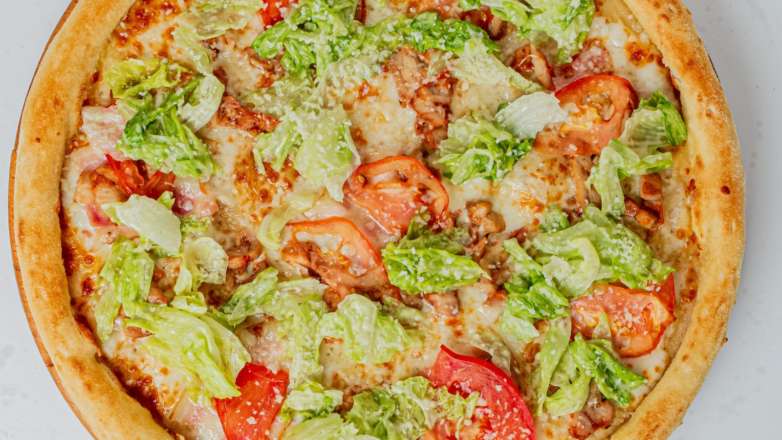 A gourmet pizza topped with fresh greens, juicy tomatoes, and savory chicken, perfectly blended to create a flavorful culinary delight that brings a taste of Italy to your table. Image Credit: maxsheb/ 123RF