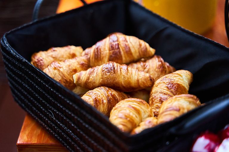 A closeup of fresh croissants in a black basket, perfect for breakfast or brunch.