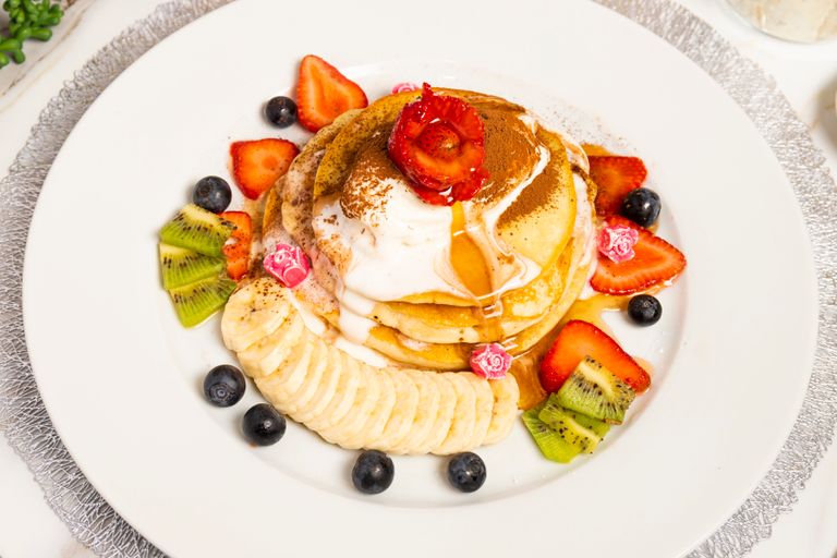 A delectable stack of pancakes topped with syrup and fresh fruit, ideal for a gourmet breakfast.