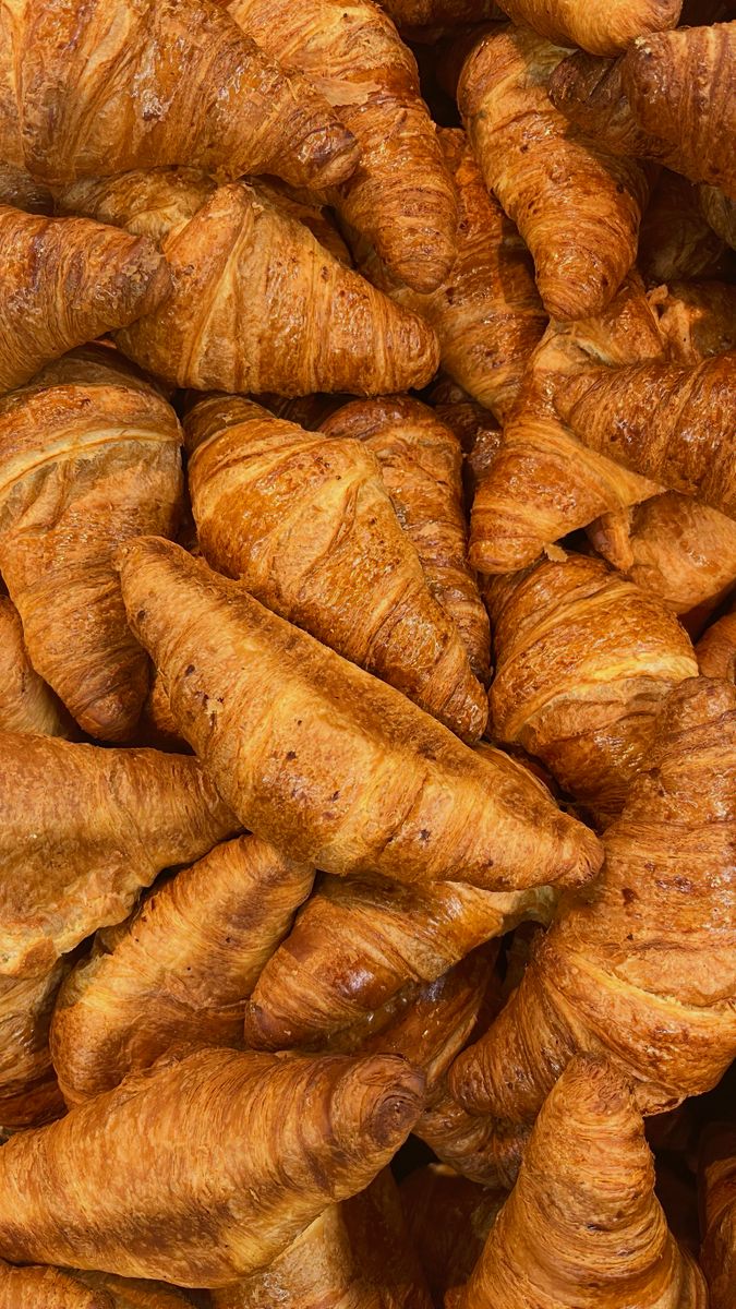 A delicious and appetizing stack of freshly baked golden croissants, capturing the essence of bakery delights.