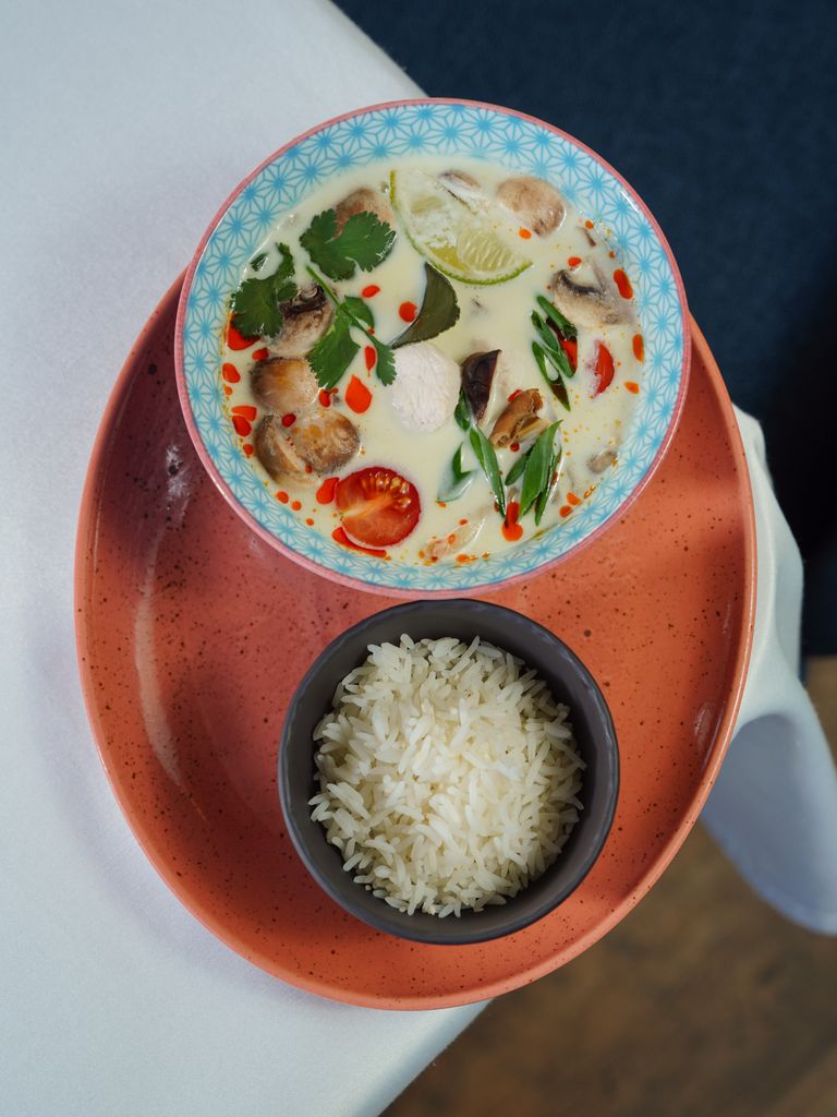 A delicious bowl of Thai Tom Kha Kai soup served with a side of rice, artfully presented.