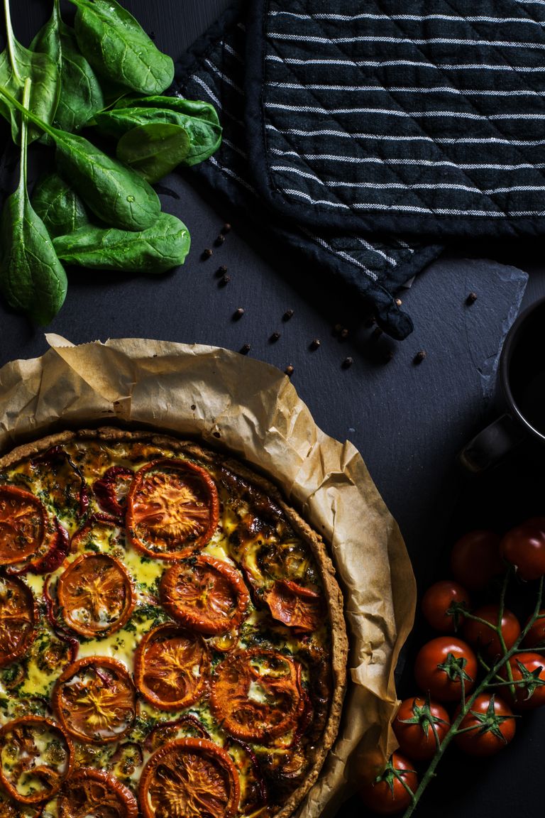 A delicious homemade tomato quiche with fresh spinach, ready to serve, perfect for dinner.