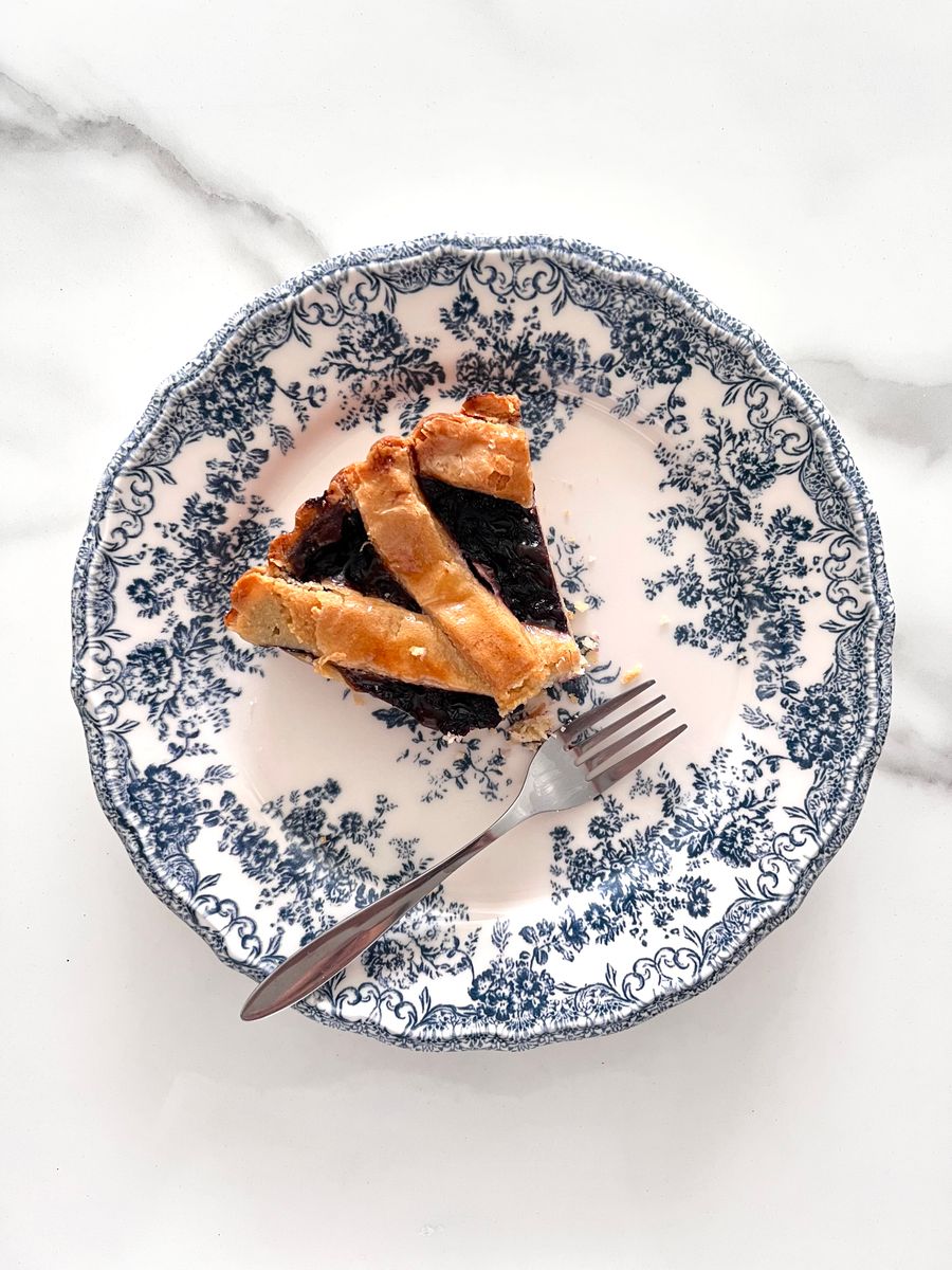 A delicious slice of blueberry pie served on an elegant blue and white vintage plate.