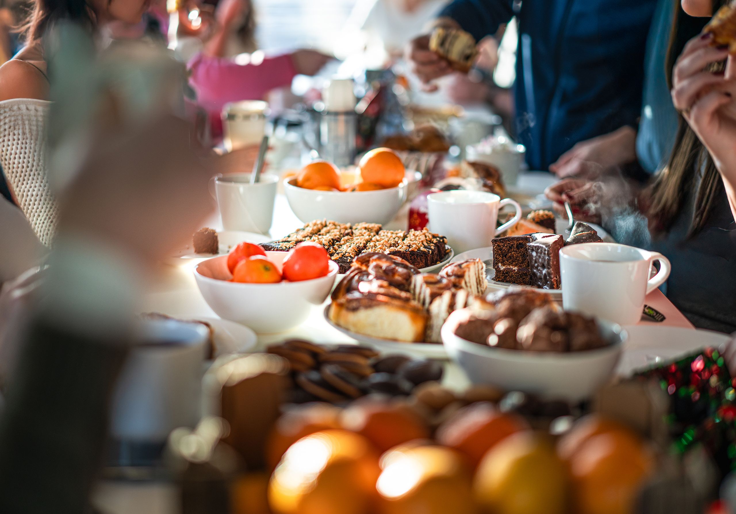 A diverse group enjoys a lively breakfast meeting with various pastries and fruits.