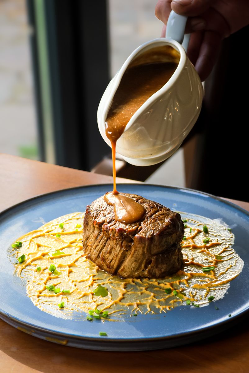 A gourmet steak served with rich gravy on a decorative plate, ideal for food enthusiasts.
