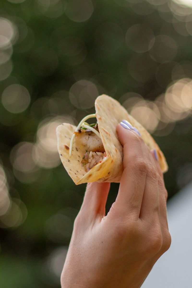 A hand holding a taco with fresh ingredients against a blurred background. Perfect for food themes.