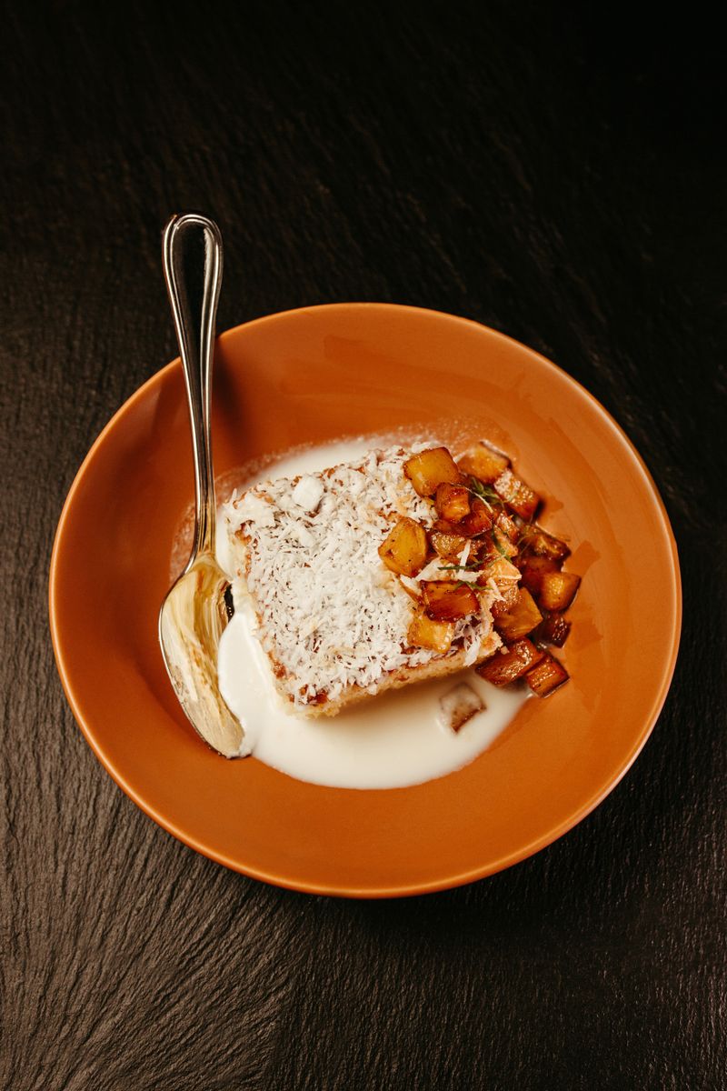 A mouthwatering slice of coconut cake with diced pineapple served on a plate.