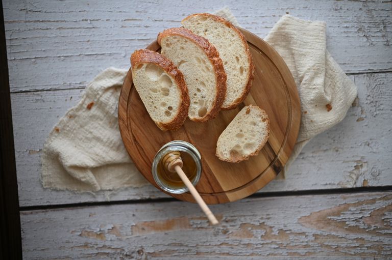 A rustic arrangement of sliced bread with honey on a wooden plate, showcasing food photography artistry.