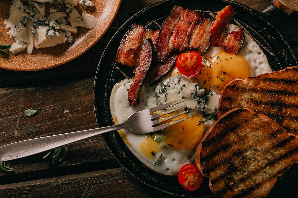 A savory breakfast skillet featuring eggs, bacon, tomatoes, and toast, perfect for a hearty meal.