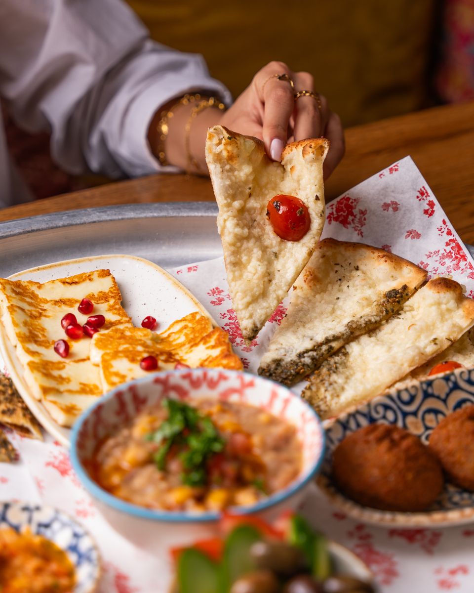 A selection of Middle Eastern dishes featuring flatbread, cheese, and dips at a restaurant.