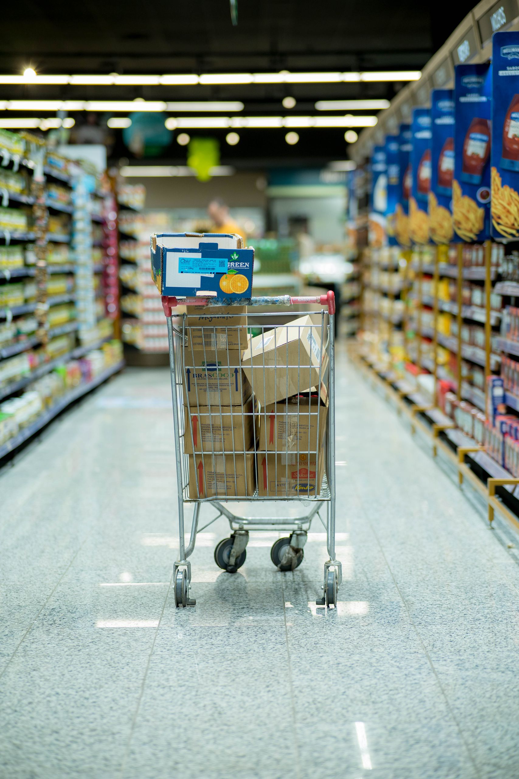 A shopping cart with packages in a grocery aisle, showcasing everyday shopping options.
