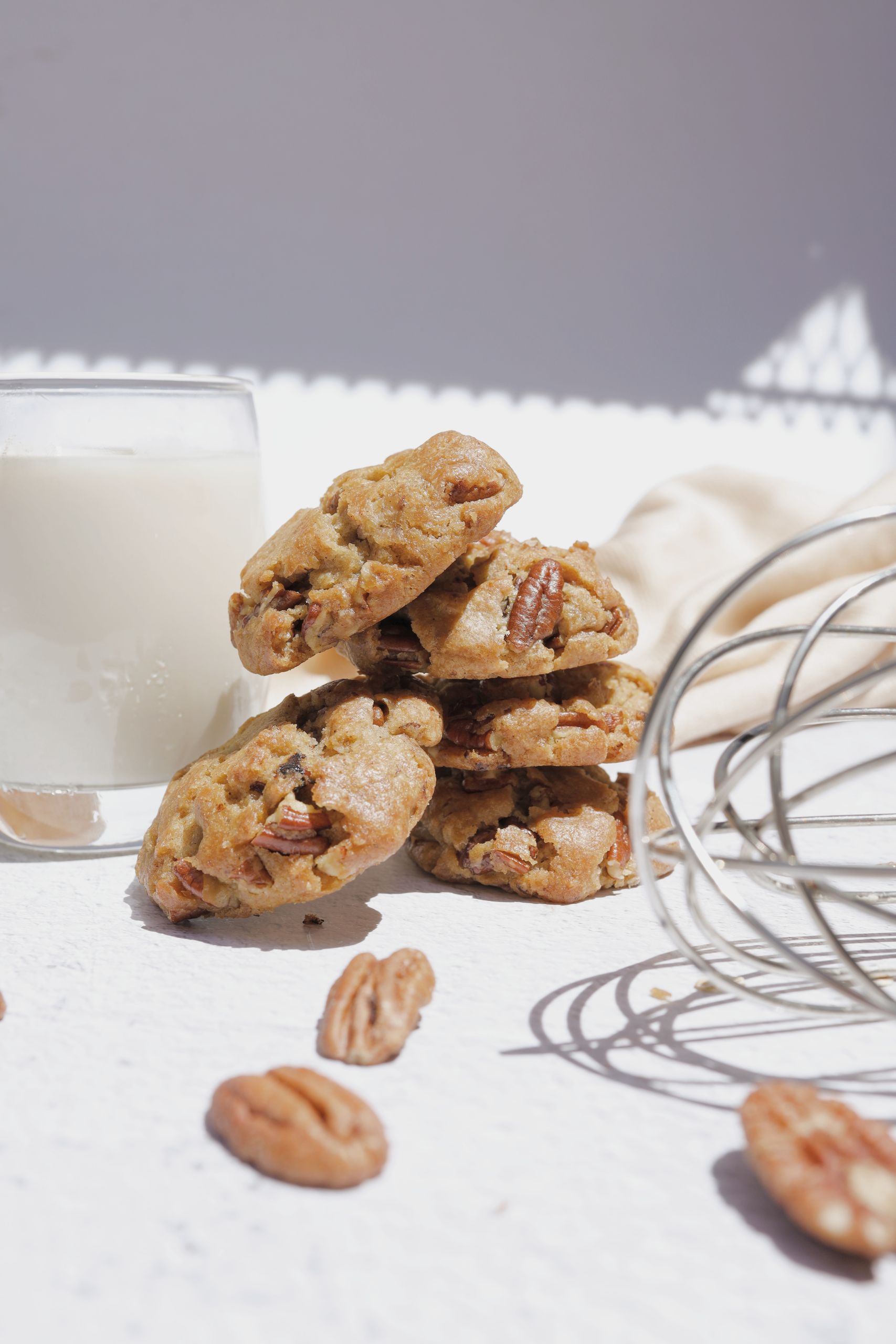 A stack of homemade pecan cookies with a glass of milk, perfect for a tasty snack.