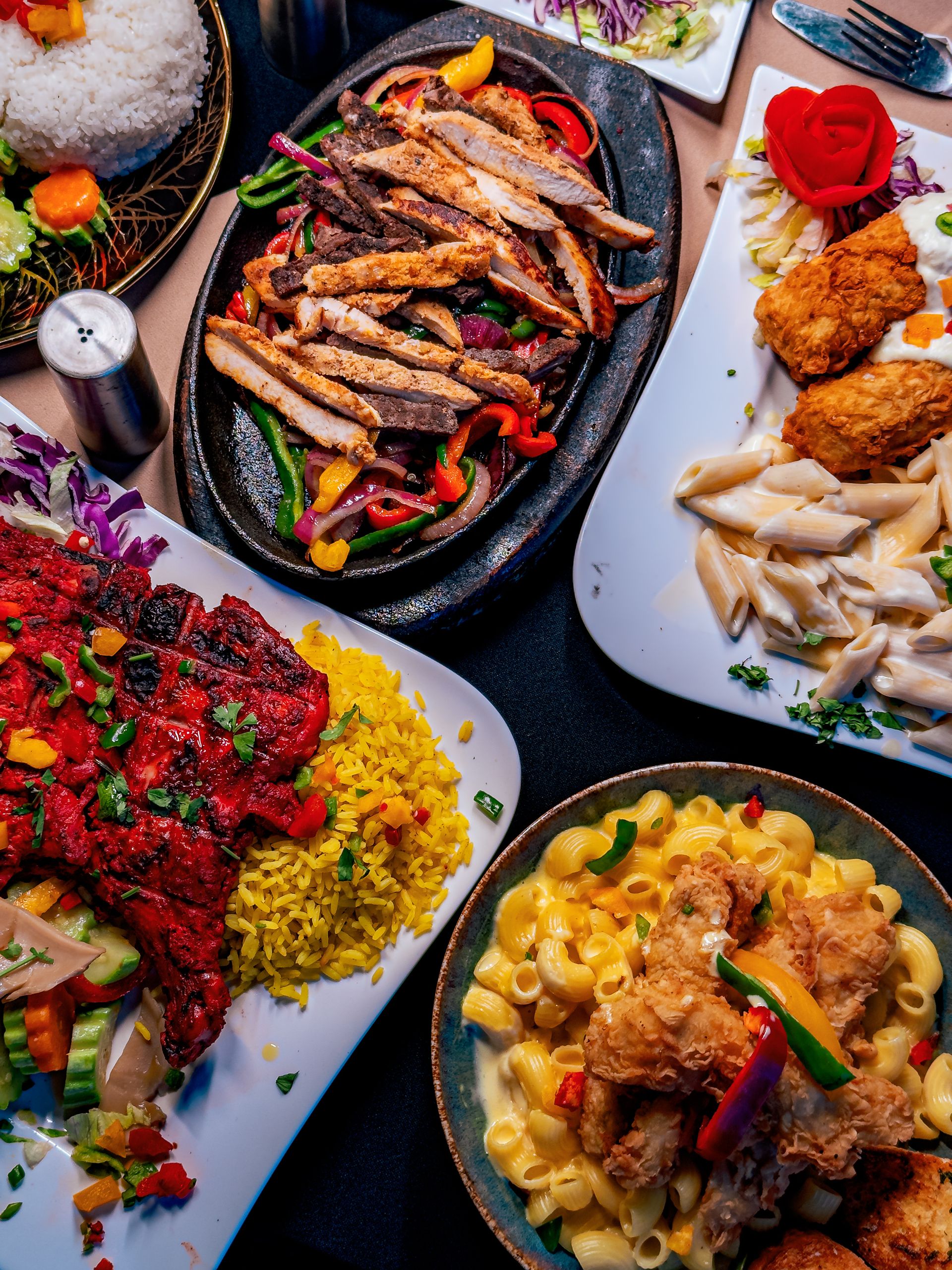 A vibrant display of assorted grilled meats and pasta dishes on a restaurant table.