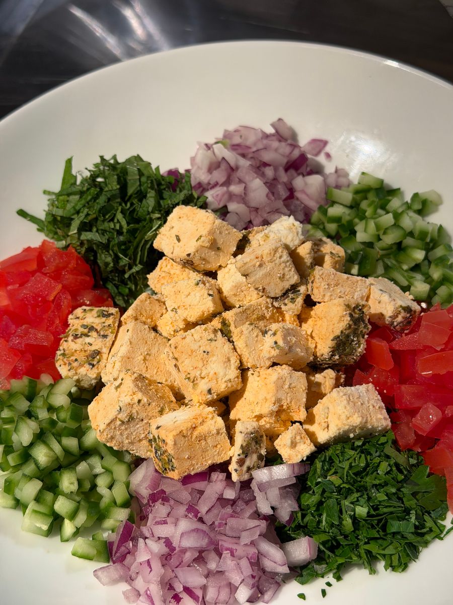 A vibrant salad featuring fresh diced vegetables and seasoned cheese cubes.