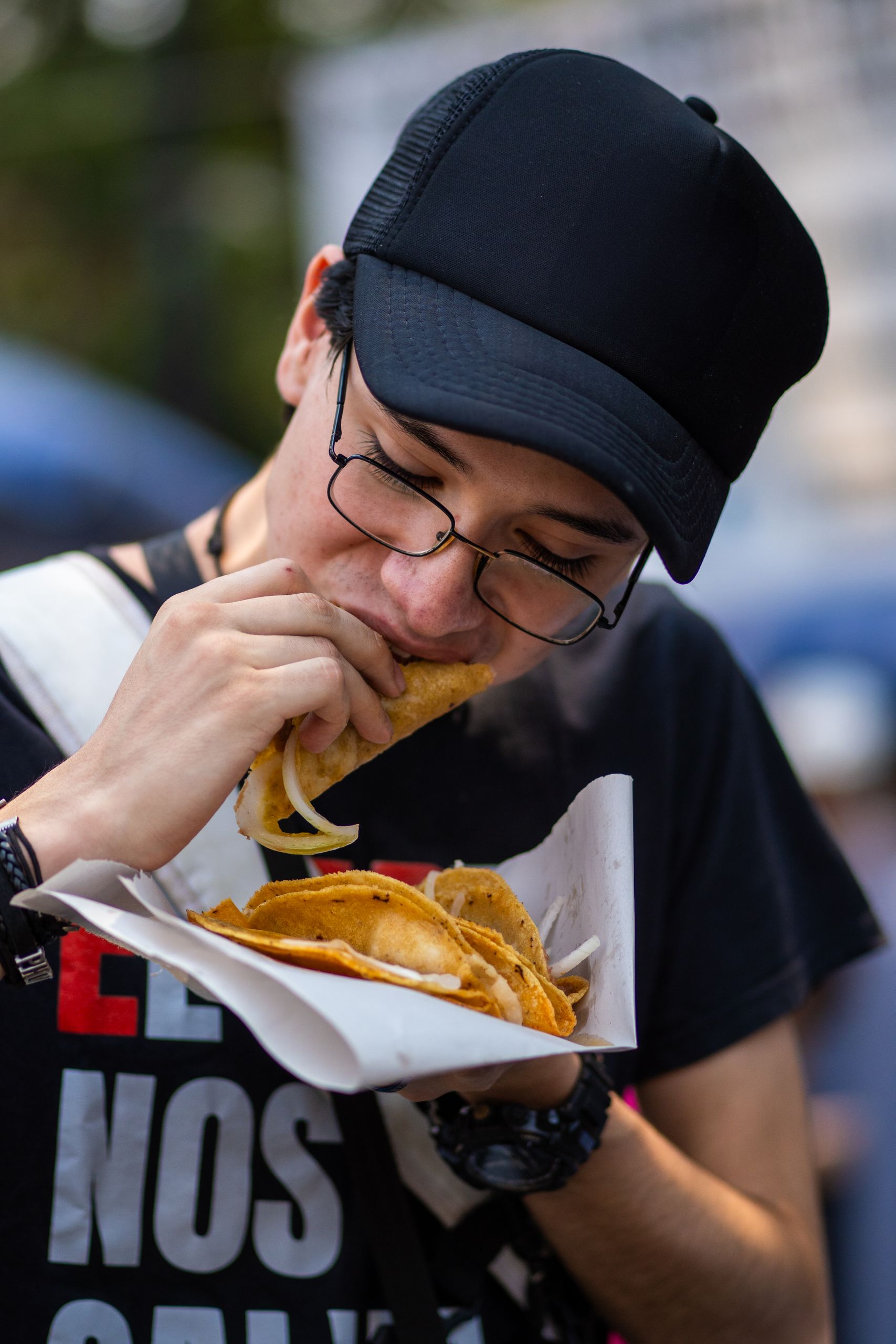 A young man savoring traditional Mexican tacos at a vibrant street market in Mexico City.