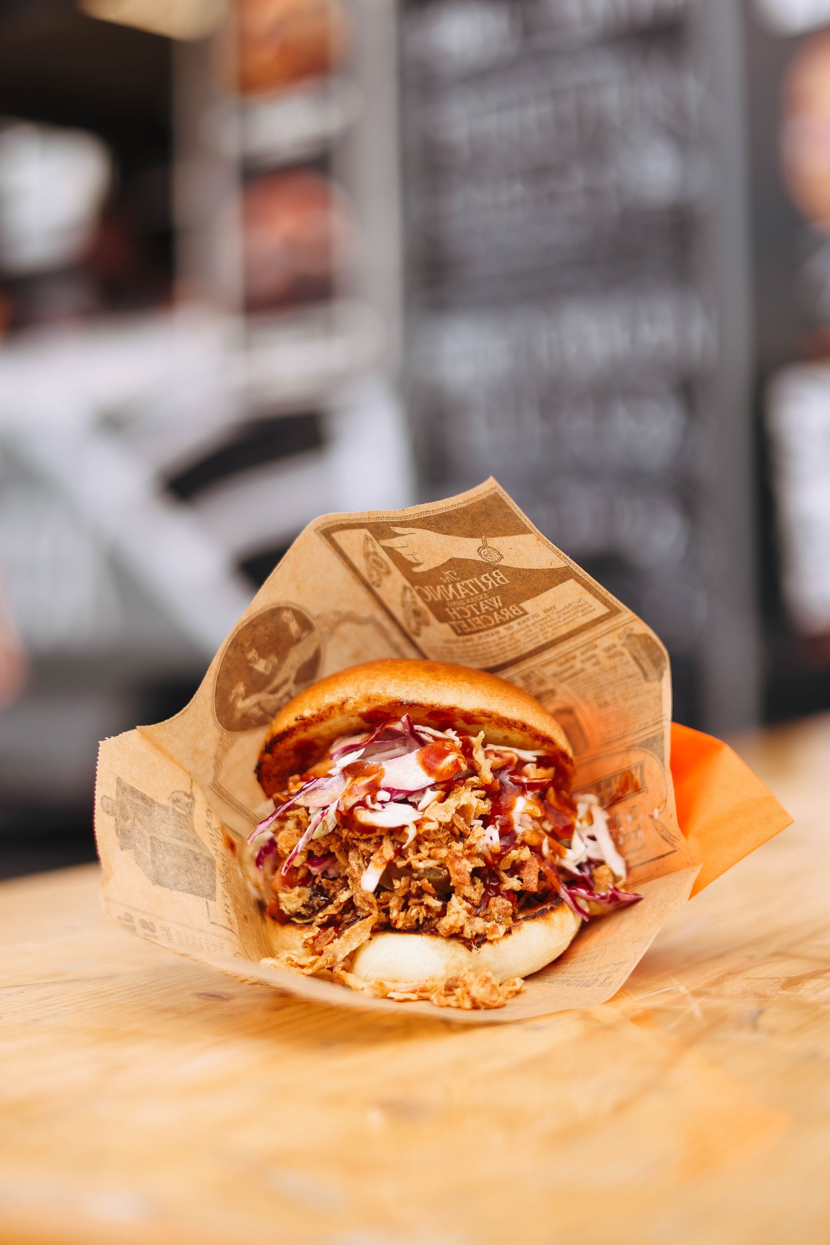 Appetizing close-up of a pulled pork sandwich with coleslaw, wrapped in paper.