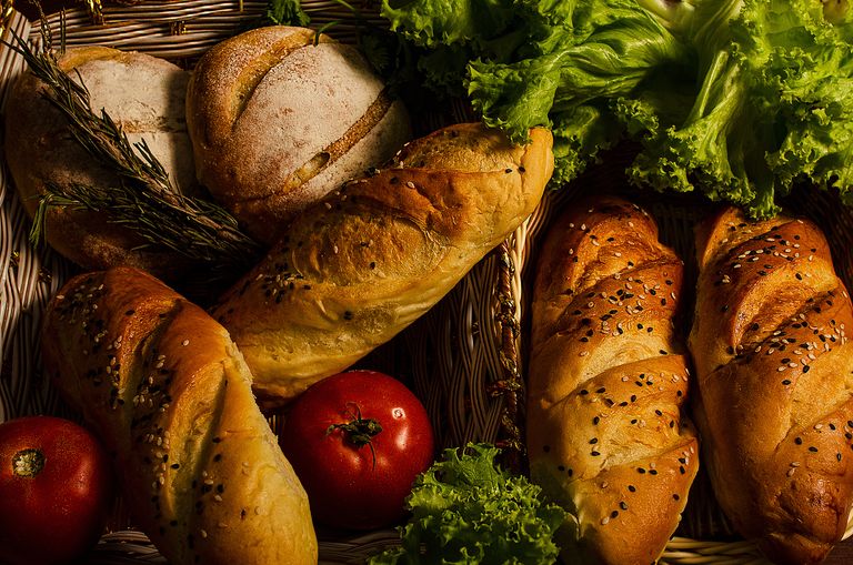 Assorted breads with fresh vegetables in a basket, showcasing a rustic and healthy meal.