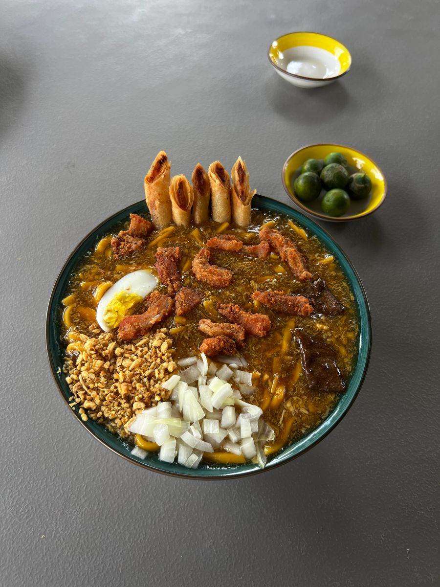 Authentic La Paz Batchoy with pork, egg, and spring rolls, served with calamansi.