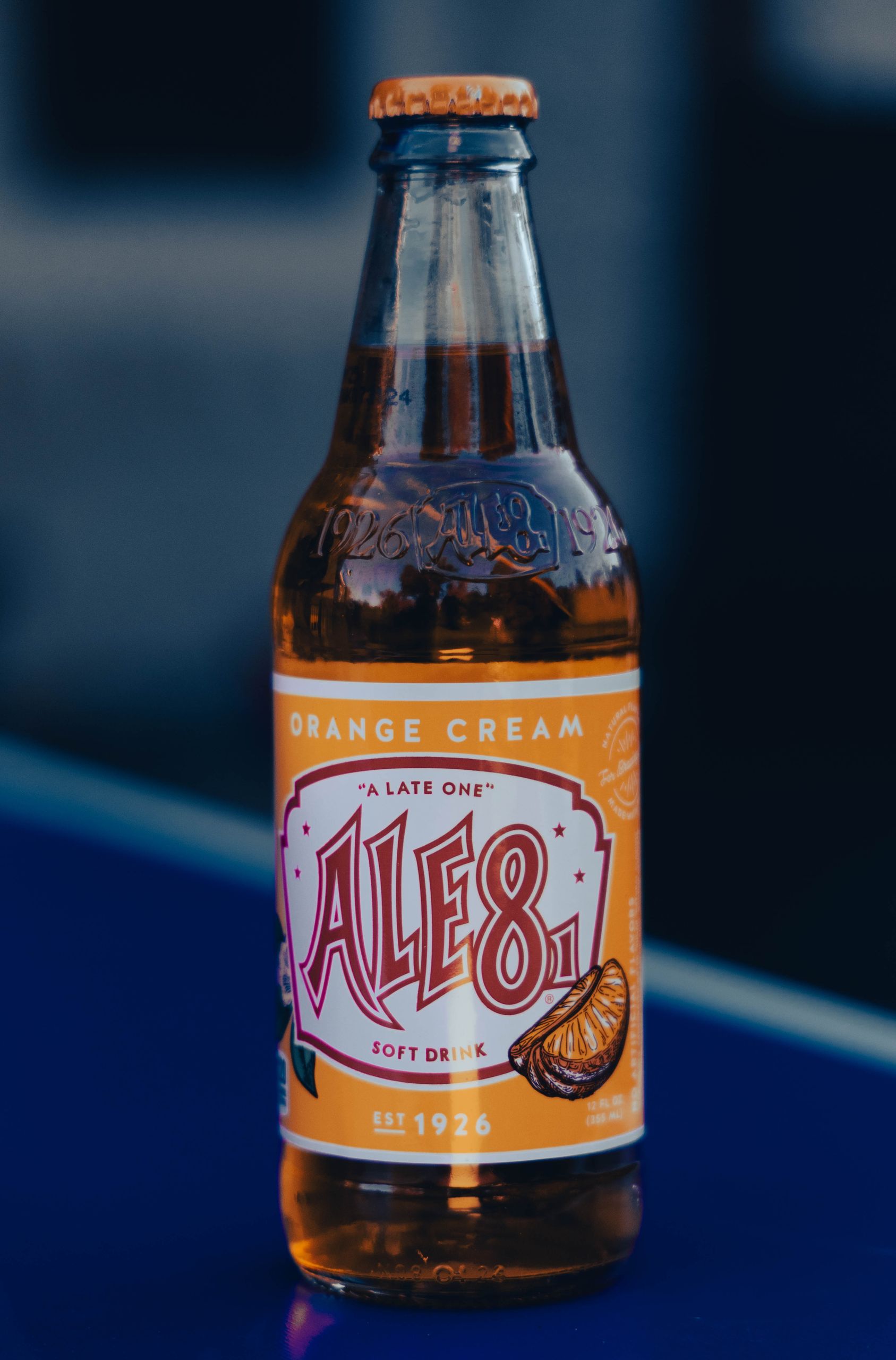 Chilled Ale-8-One Orange Cream soda bottle displayed against a blurred background, showcasing its unique flavor.