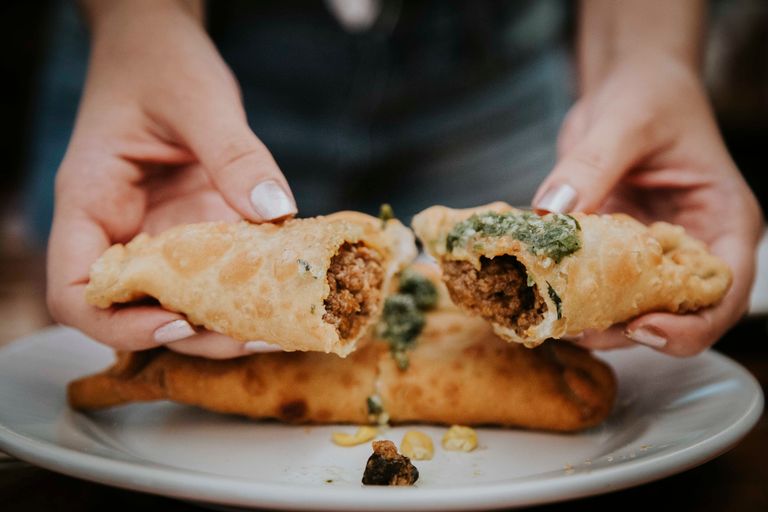 Close-up of a beef empanada being split open, showcasing savory filling. Ideal for culinary and cuisine themes.