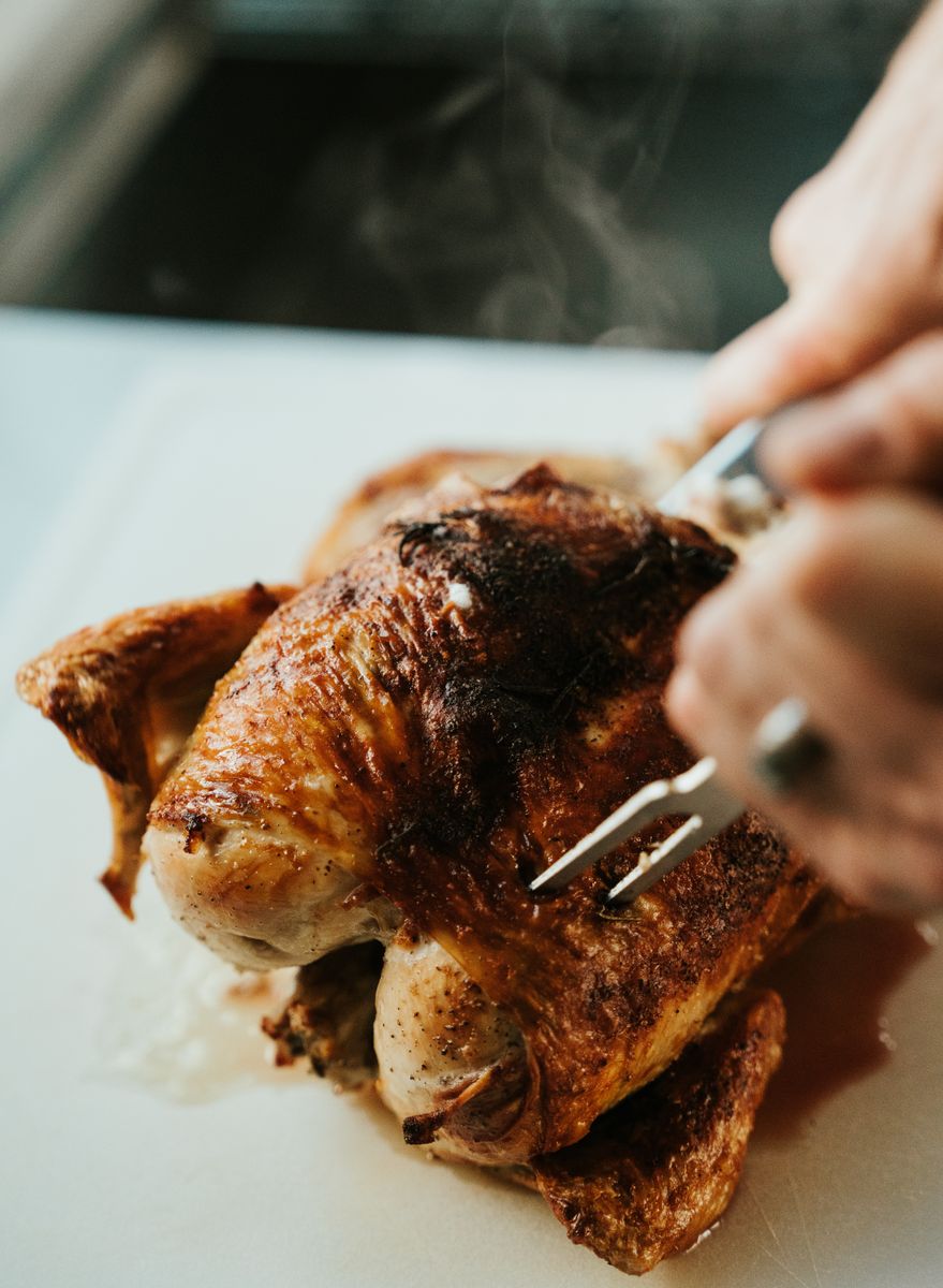 Close-up of a freshly roasted chicken being carved with a fork. Steamy and delicious.