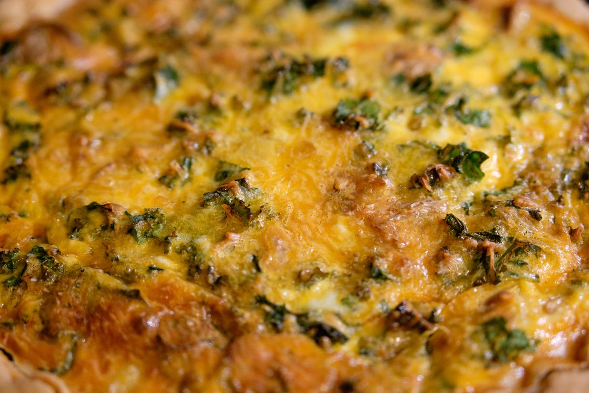 Close-up of a golden, cheesy quiche with kale, perfect for breakfast or brunch.