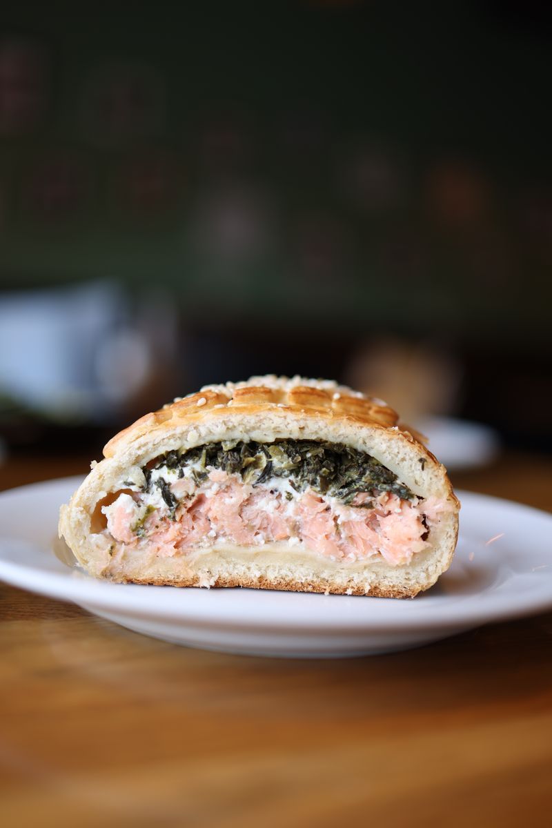 Close-up of a gourmet salmon and spinach pastry on a plate, perfect for food photography.