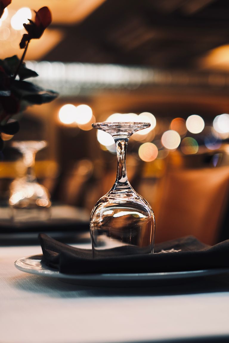 Close-up of an upside-down wineglass on a table with bokeh lights in the background.