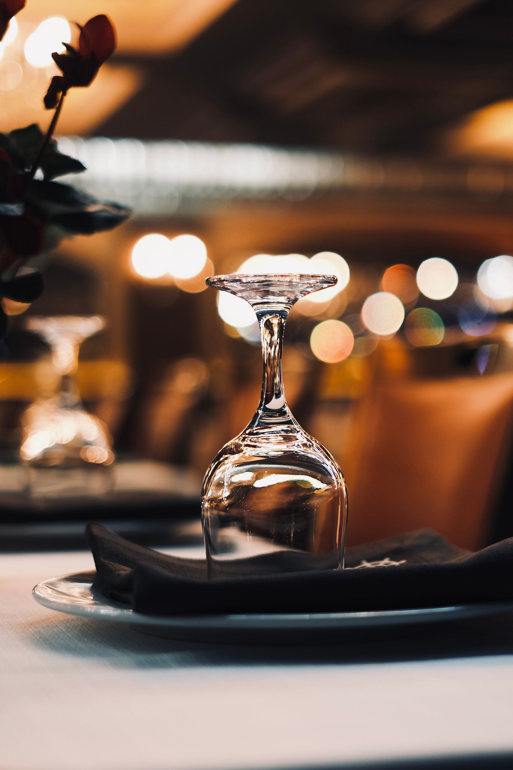 Close-up of an upside-down wineglass on a table with bokeh lights in the background.