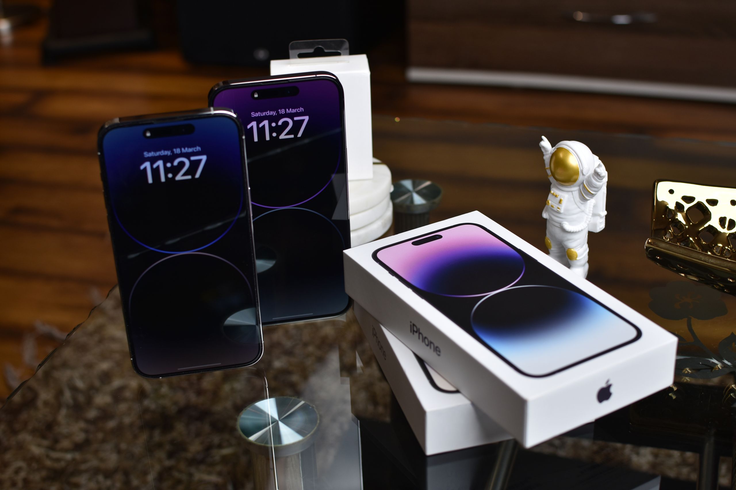 Close-up of Apple iPhone 14 Pro Max with astronaut figurine on a reflective surface.