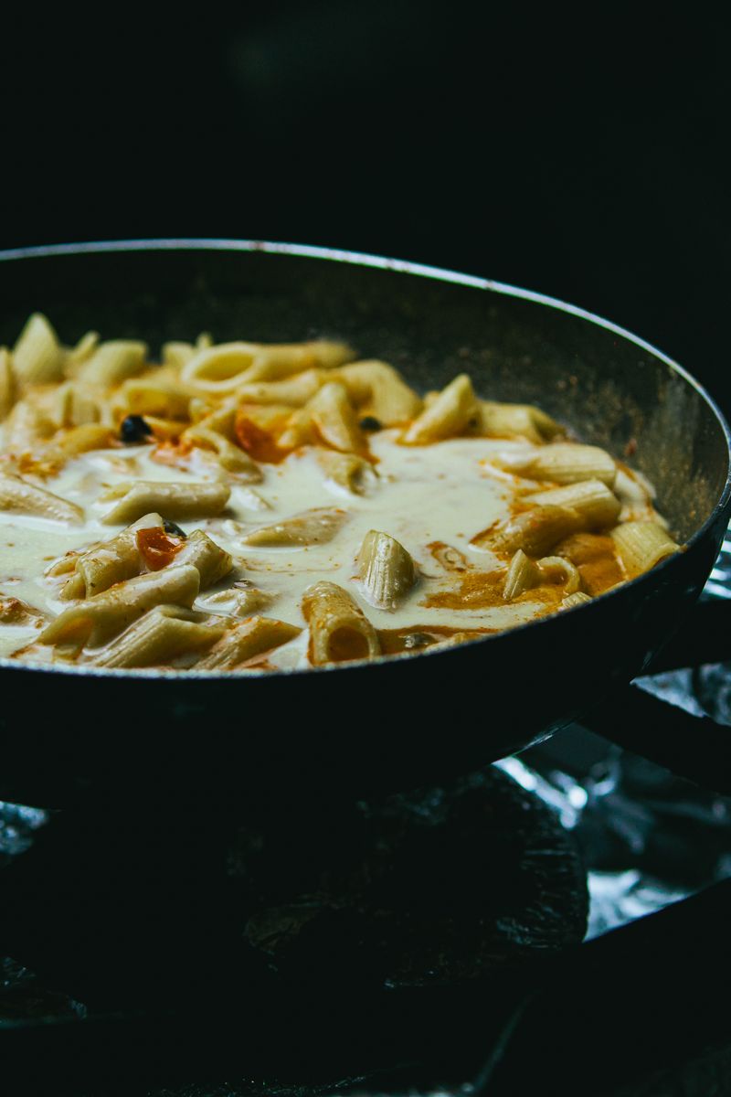 Close-up of creamy pasta with penne cooking in a skillet.