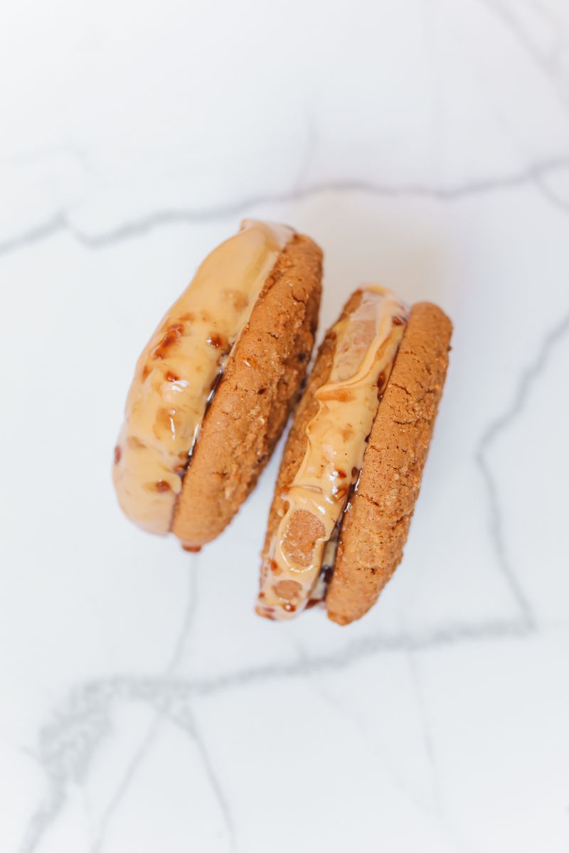 Close-up of ice cream-filled cookie sandwiches on a marble surface, showcasing sweet temptation.