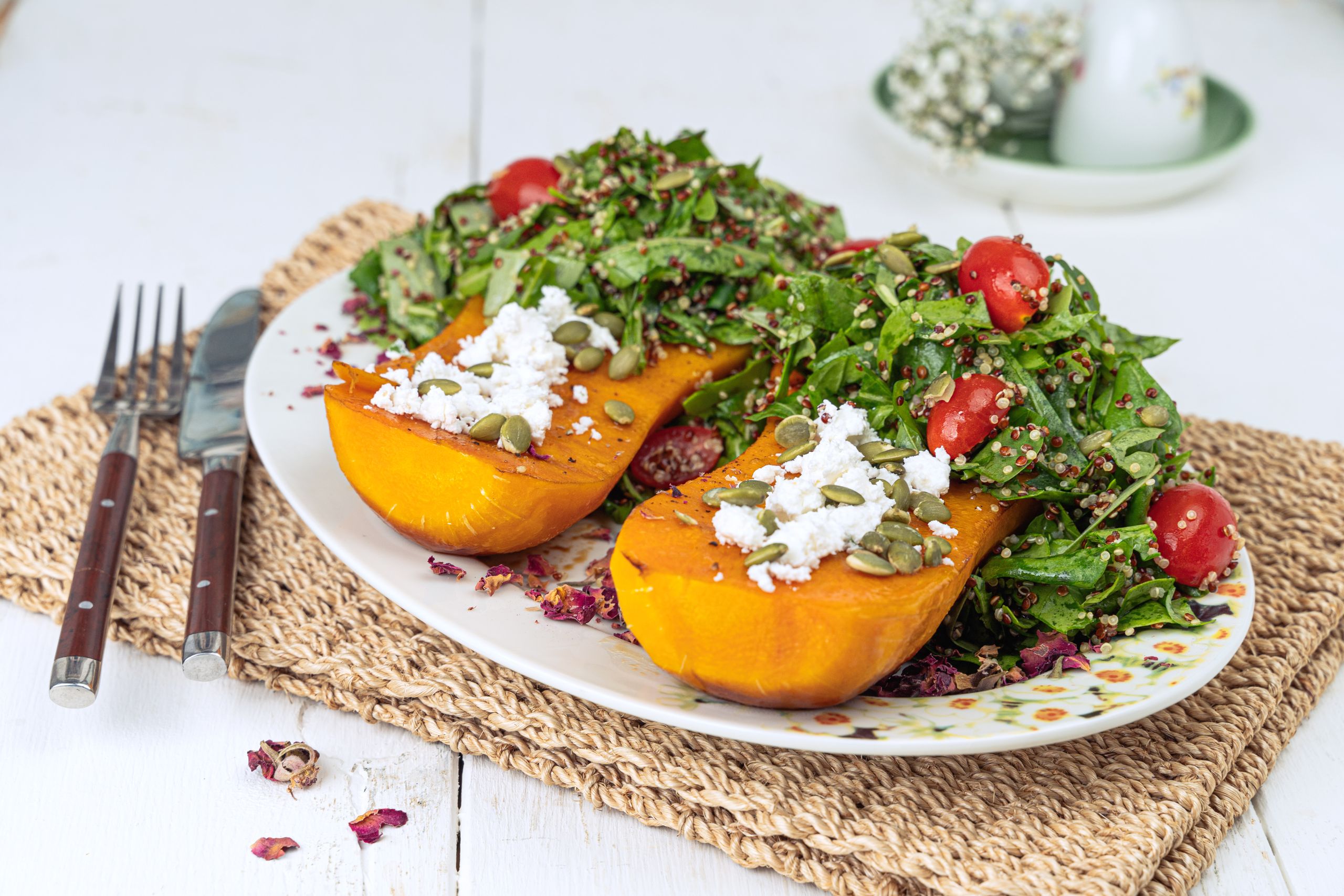 Close-up of roasted butternut squash with quinoa salad, cherry tomatoes, and feta.