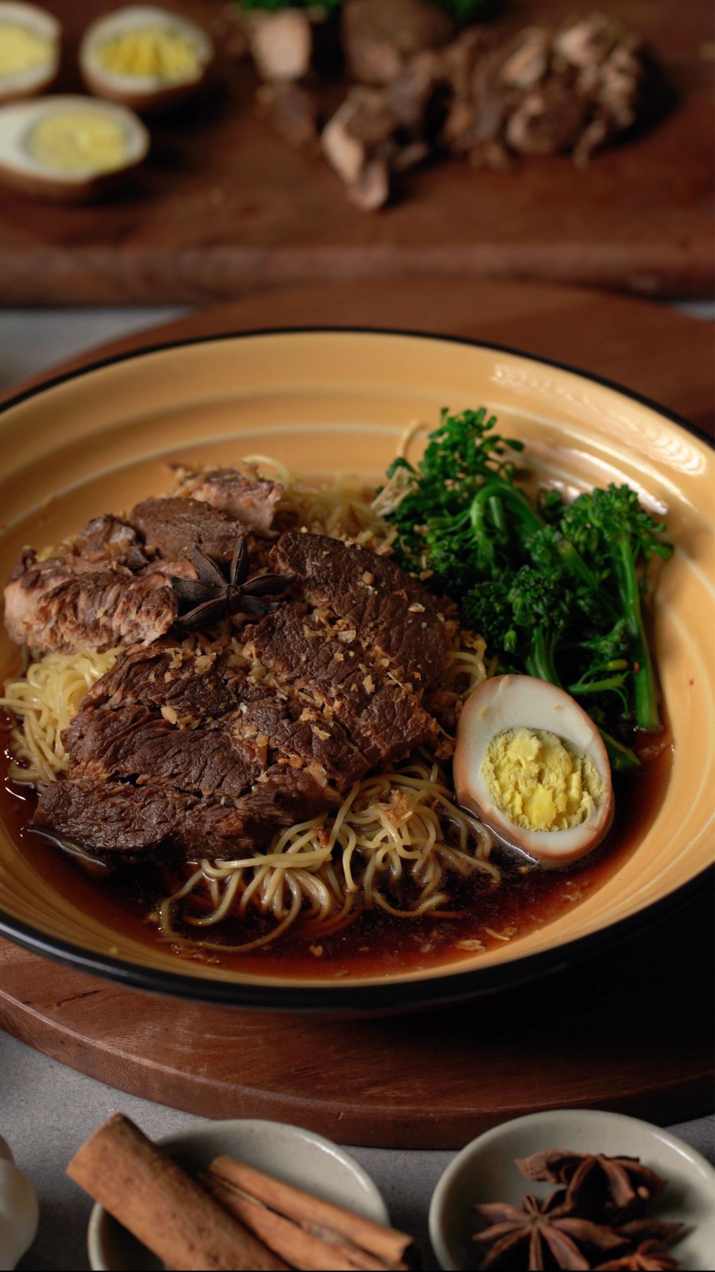 Close-up of savory beef ramen with egg and fresh broccoli in a bowl.