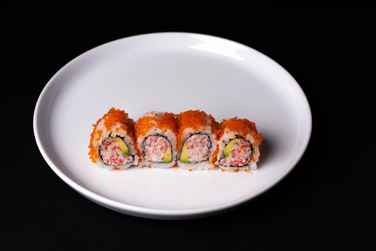 Close-up of sushi rolls with vibrant salmon roe on a pristine white plate, perfect for food presentations.