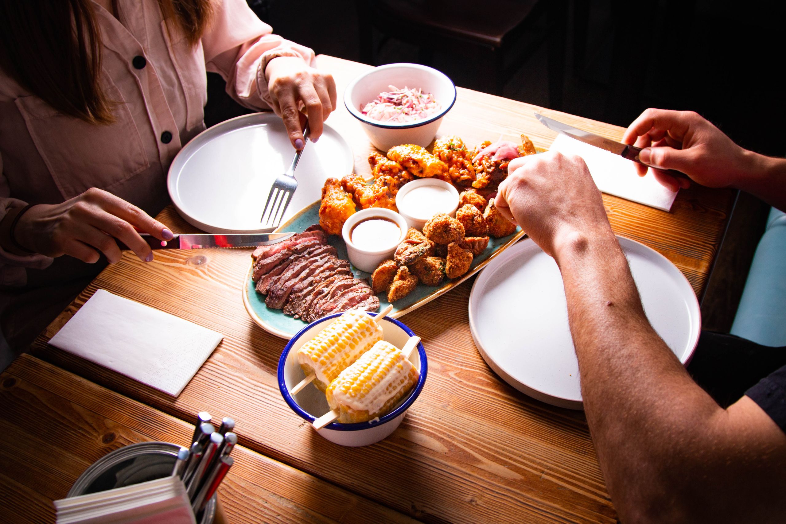Couple dining with assorted tasty dishes including meat and corn in Vienna restaurant.