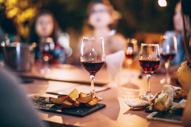 Cozy dinner party atmosphere featuring red wine, snacks, and blurred social gathering.