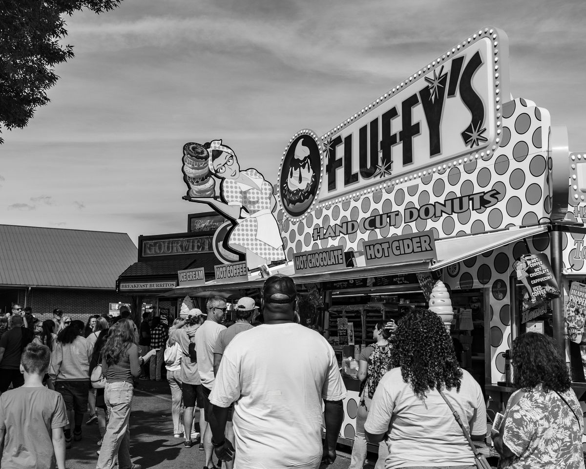 Crowd gathered at Fluffy's hand-cut donuts stand during a fair.