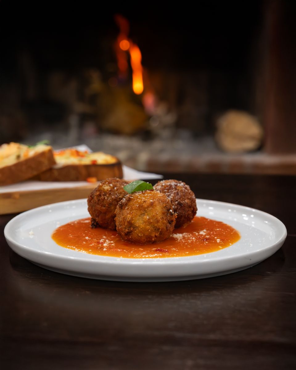 Delicious arancini served on a bed of tomato sauce in a warm, cozy restaurant ambiance.