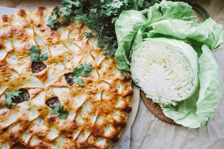 Delicious baked pie with a golden crust, paired with fresh cabbage and greens, ideal for savory food lovers.
