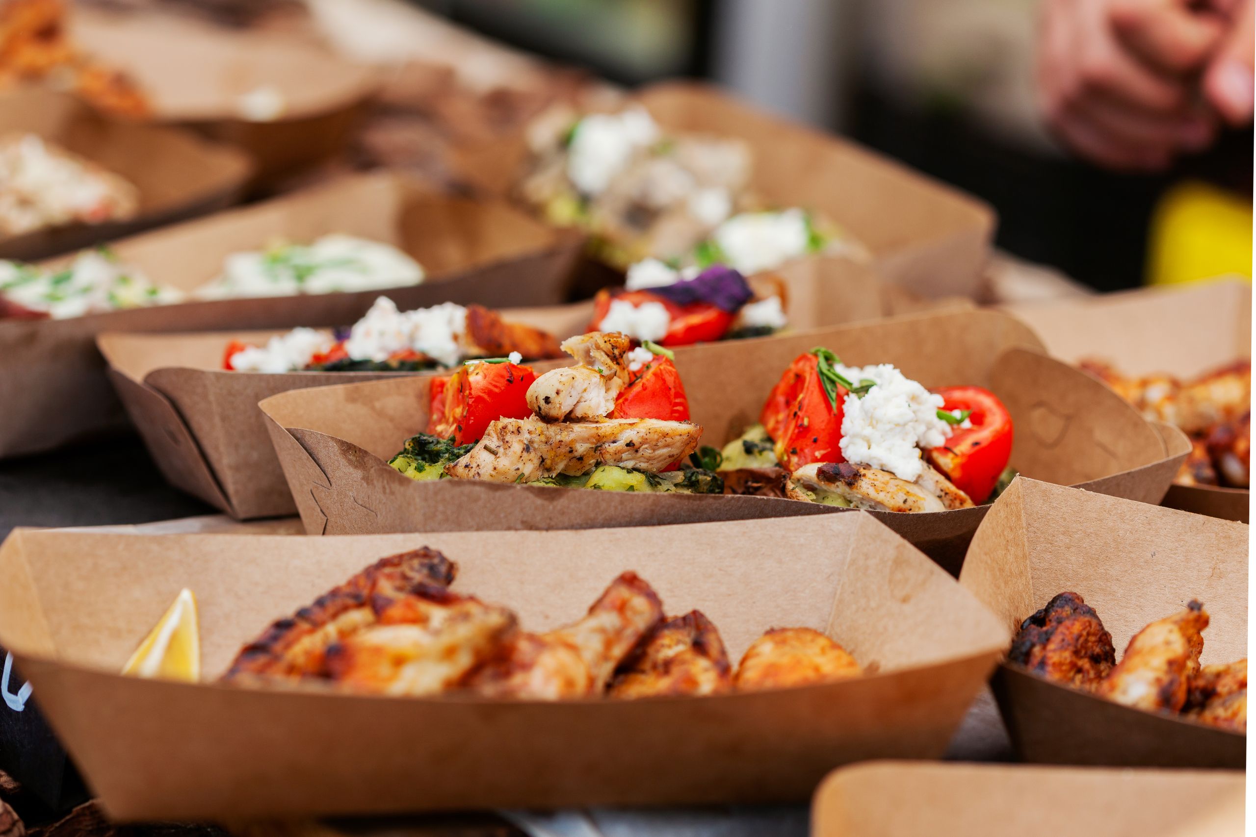 Delicious chicken dishes with vegetables served in eco-friendly paper containers.
