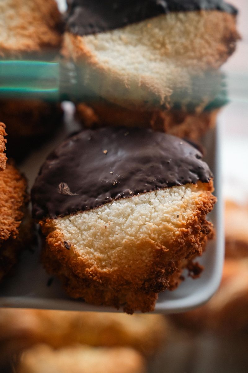 Delicious chocolate-coated coconut macaroons on a plate, sweet treat.