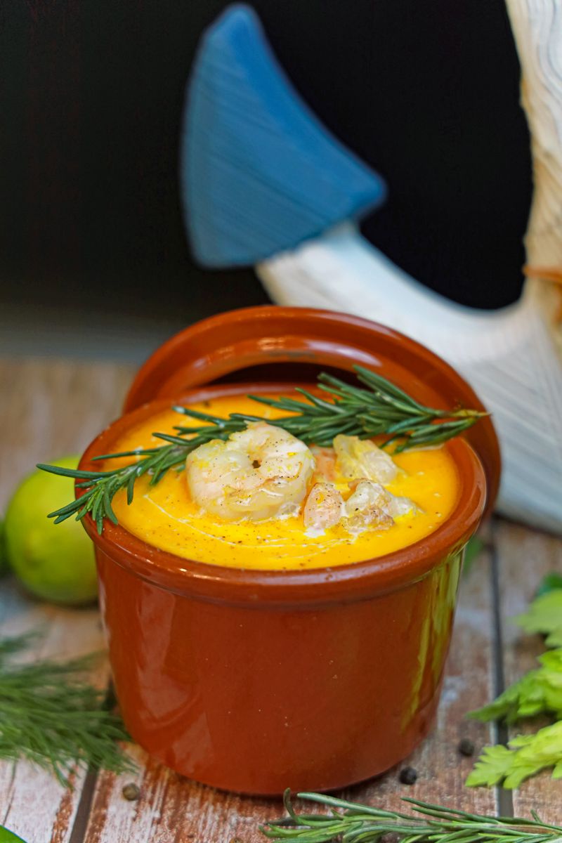 Delicious creamy shrimp dish garnished with rosemary, served in a rustic pot.